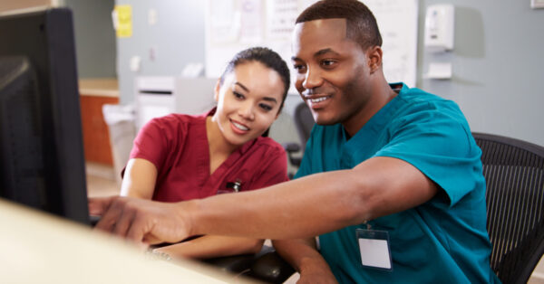 Two healthcare practitioners pointing to information on a computer
